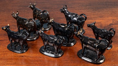 Lot 99 - A herd of eight black glazed and parcel gilt North Country pottery cow creamers