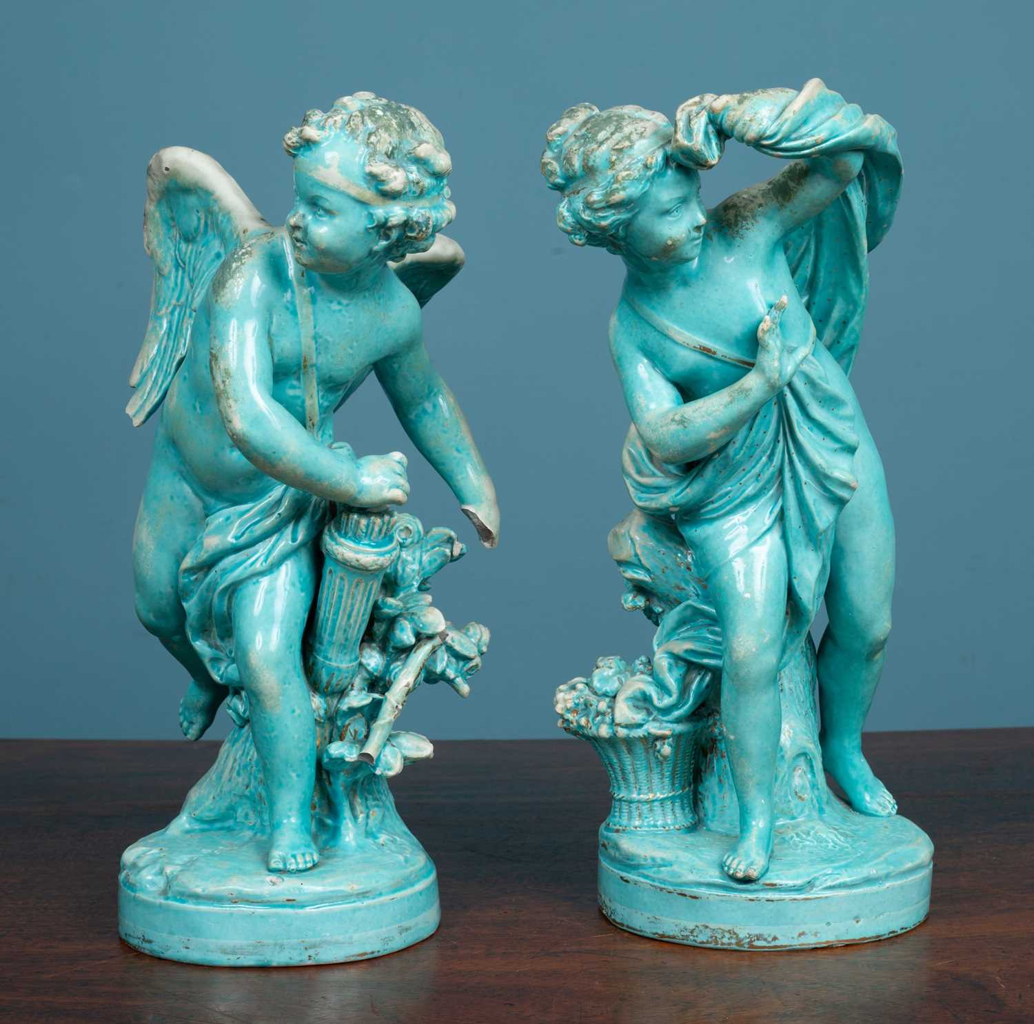 Lot 7 - A pair of Continental turquoise glazed pottery figures of Cupid and Psyche