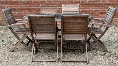 Lot 1266 - A folding teak garden dining table with a set of six matching folding chairs