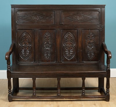 Lot 464 - An antique oak high back settle with carved panels