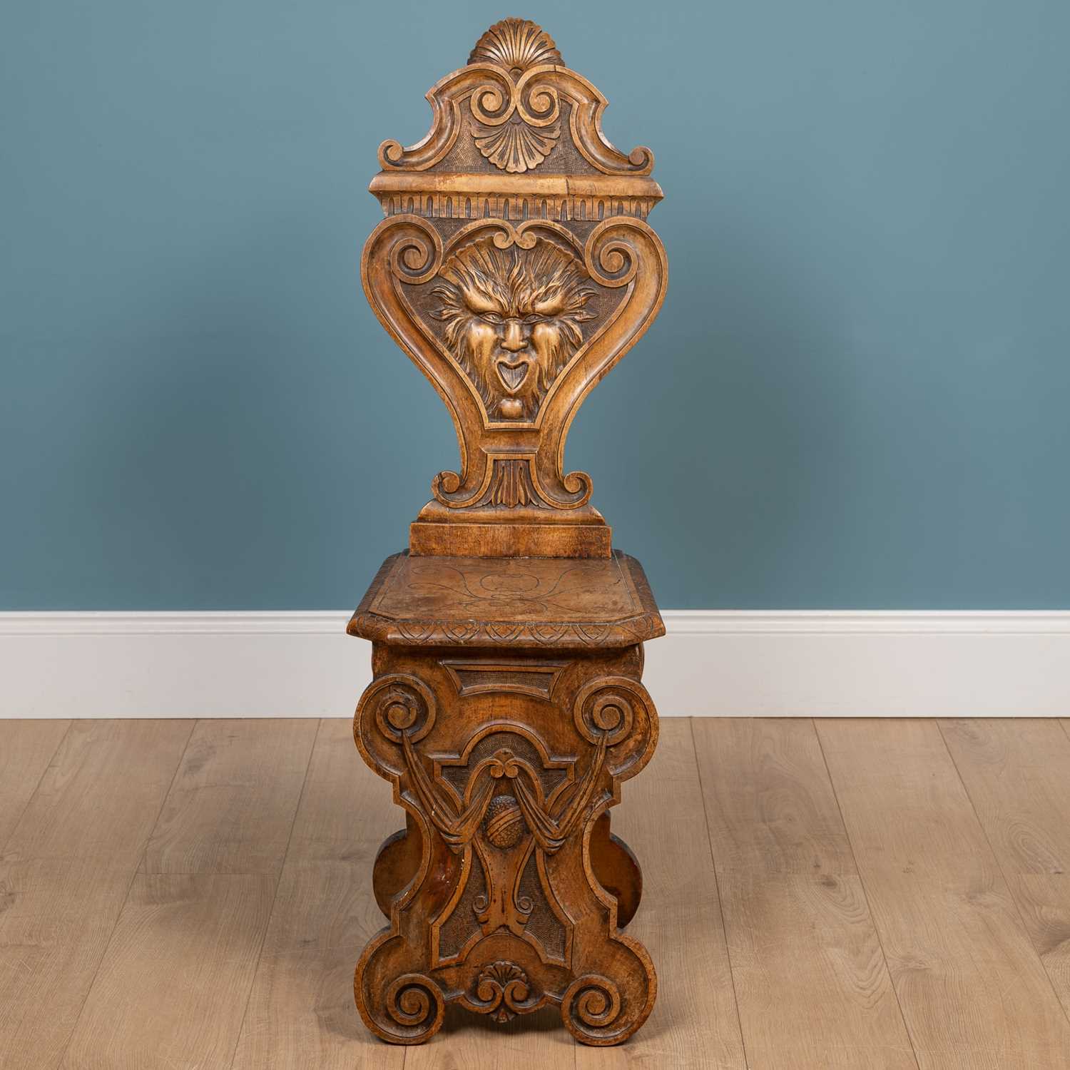 Lot 562 - A heavily carved Sgabello style Italian walnut hall chair