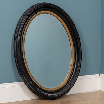 Lot 453 - An oval wall mirror with an ebonised frame