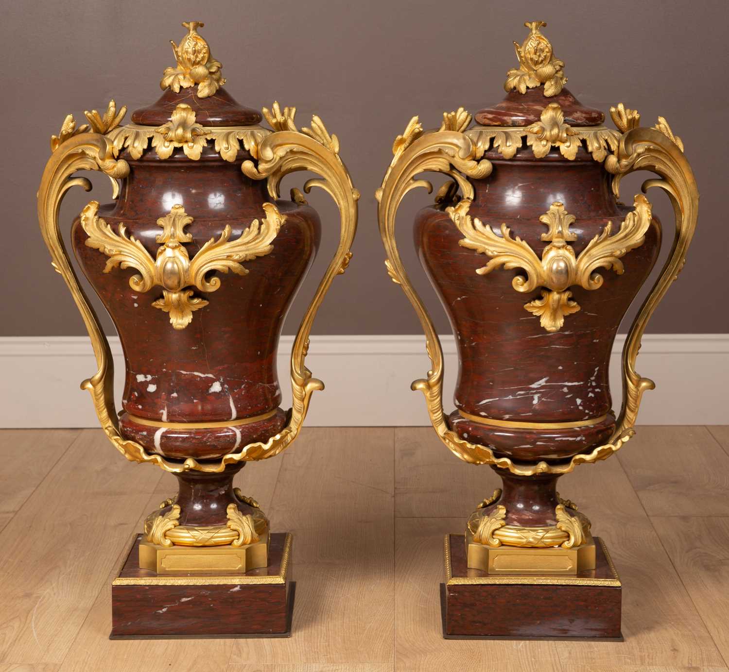 Lot 158 - A pair of French Empire style rouge marble lidded urns