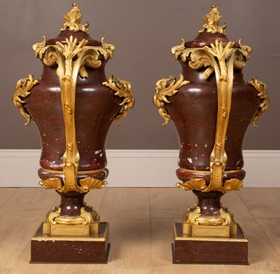 Lot 158 - A pair of French Empire style rouge marble lidded urns