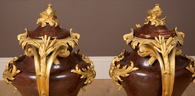 Lot 158 - A pair of French Empire style rouge marble lidded urns