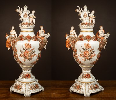 Lot 430 - A pair of German porcelain urns on stands with the handles modelled as maidens