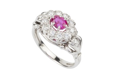 Lot 210 - A ruby and diamond cluster ring, the oval cut...