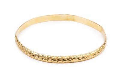 Lot 285 - A yellow precious metal bangle, with engraved...