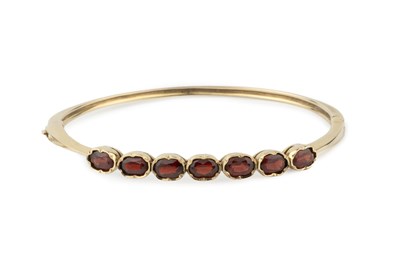 Lot 29 - A 9ct gold and garnet hinged bangle, set with...