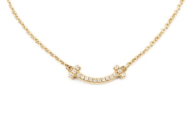 Lot An 18ct gold and diamond T-Smile necklace by...