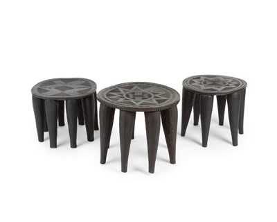 Lot 1084 - A group of three ebonised African stools