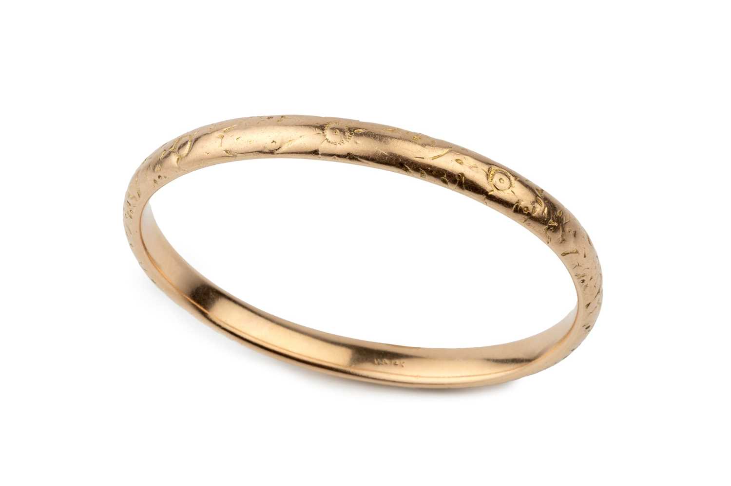 Lot A 14k gold oval bangle, engraved with stylised...