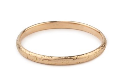 Lot A 14k gold oval bangle, engraved with stylised...