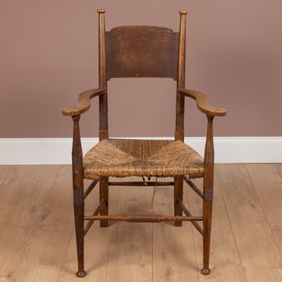 Lot 1143 - An Arts and Crafts style rush seated oak framed armchair