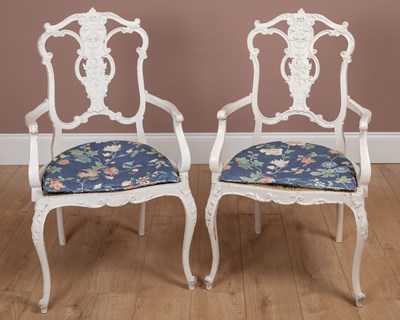 Lot 1185 - A pair of white painted carved wood elbow chairs