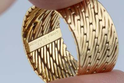 Lot 253 - A dress ring by Hermès, the wide band of...