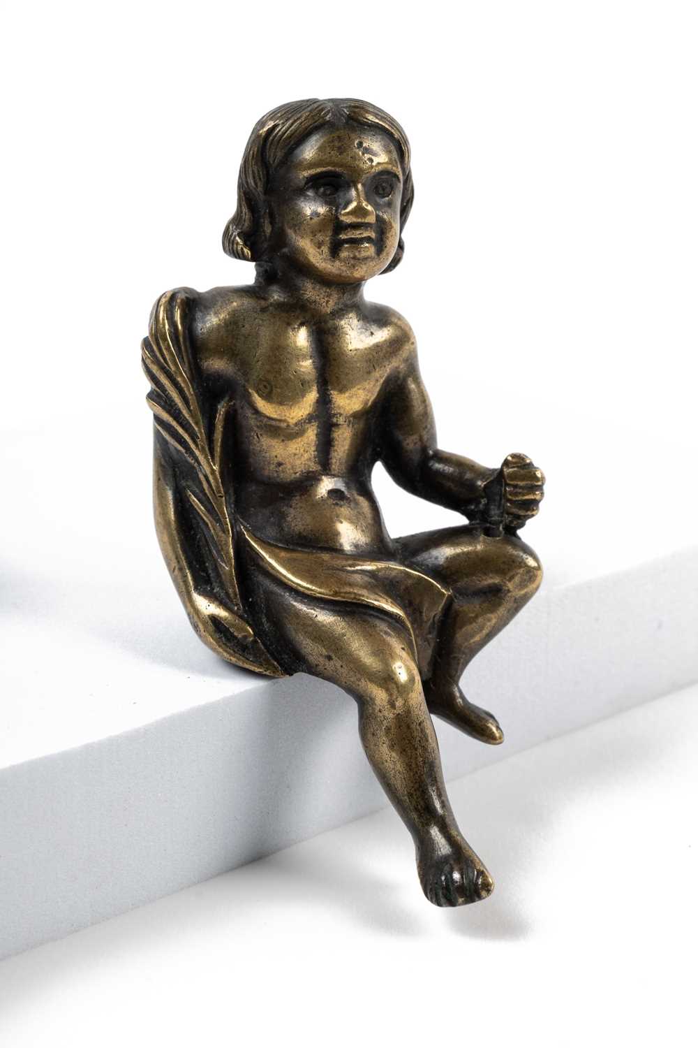 Lot 119 - A small classical bronze sculpture of a seated boy holding a palm frond