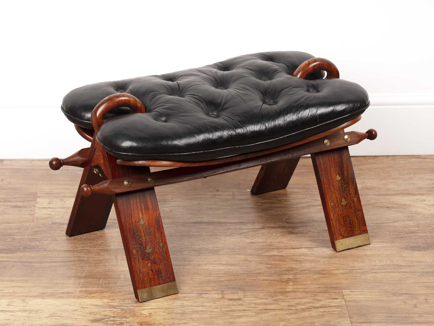 Lot 56 - Camel saddle stool 20th Century, with black...