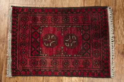 Lot 151 - Small red ground wool rug with two medallions,...