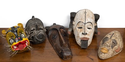 Lot 233 - A collection of four African carved masks and one further mask