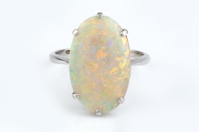 Lot An opal single stone ring, the oval cabochon...