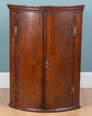 Lot 335 - A George III walnut bow-fronted hanging corner cupboard