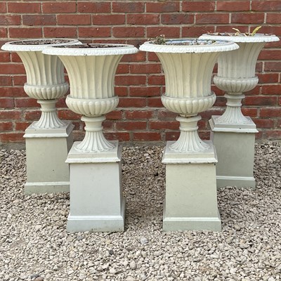 Lot 1305 - A set of four cast iron urns on plinths
