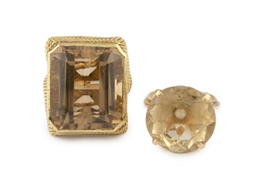 Lot 64 - Two citrine single stone dress rings, the...