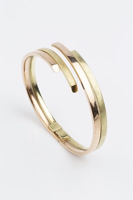 Lot 158 - A two colour precious metal bangle, of hinged...