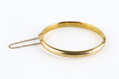 Lot 11 - A late Victorian gold bangle, of hinged oval...