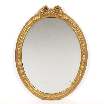 Lot 164 - An oval gilt framed wall mirror with ribbon...