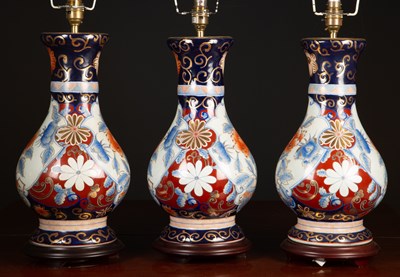 Lot 490 - A set of three porcelain table lamps decorated...