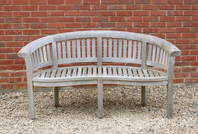 Lot 851 - A curving teak garden bench with serpentine...