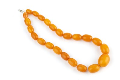 Lot 27 - An amber bead necklace, comprising a single...