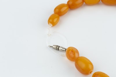Lot 27 - An amber bead necklace, comprising a single...