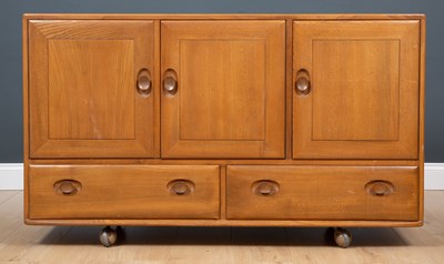 Lot 412 - A 1970's Ercol light elm three-door sideboard,...