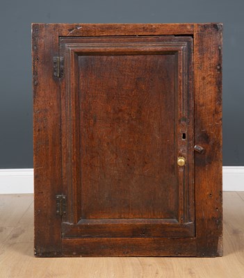 Lot 414 - An antique oak wall cupboard the moulded panel...